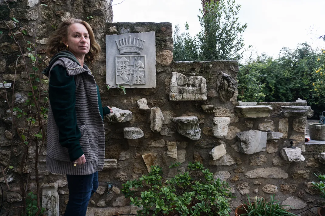 Despoina Stratigis stands next to ancient ruins in her garden.